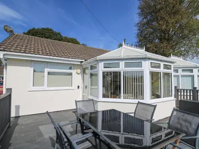a house with a table and chairs on a patio at Trem-Yr-Afon in Lampeter