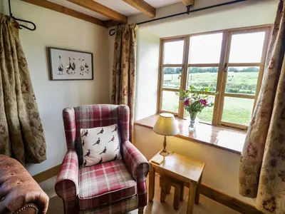 a living room with a chair and a window at Grove Farm in Church Stretton