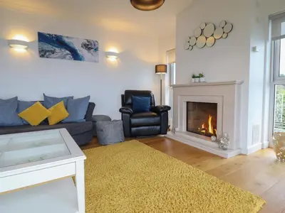 a living room with a couch and a fireplace at Gwylanod in Llwyngwril