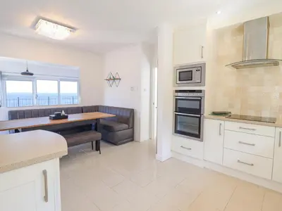 a kitchen with white cabinets and a table and a counter at Gwylanod in Llwyngwril
