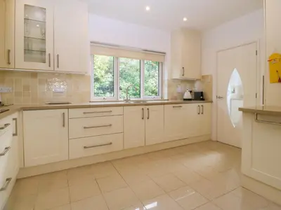 a large kitchen with white cabinets and a window at Gwylanod in Llwyngwril