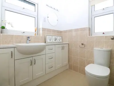 a bathroom with a sink and a toilet and two windows at Gwylanod in Llwyngwril