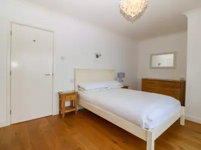 a bedroom with a white bed and a chandelier at Gwylanod in Llwyngwril