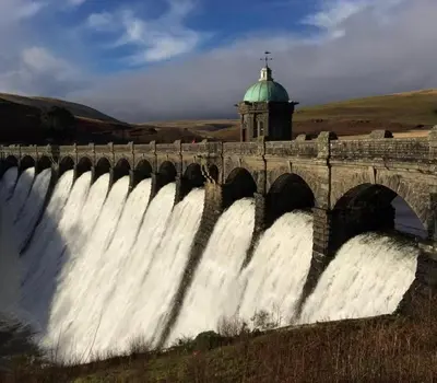 a bridge over a waterfall with a green dome at Glamping Life Retreat in Nantmel