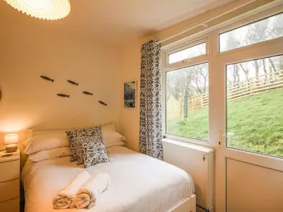 a bedroom with a bed and a large window at The Glass House in Aberdyfi