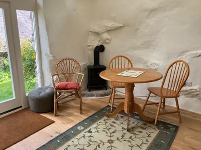 a room with a table and two chairs and a stove at Studio in medieval Welsh farmhouse in Aber Cowarch