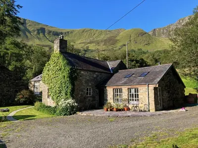 a stone house with ivy on the side of a road at Studio in medieval Welsh farmhouse in Aber Cowarch
