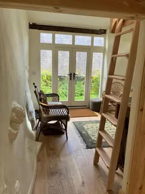 a room with a ladder and a chair and a door at Studio in medieval Welsh farmhouse in Aber Cowarch