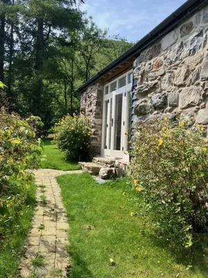 a stone house with a white window and a path at Studio in medieval Welsh farmhouse in Aber Cowarch