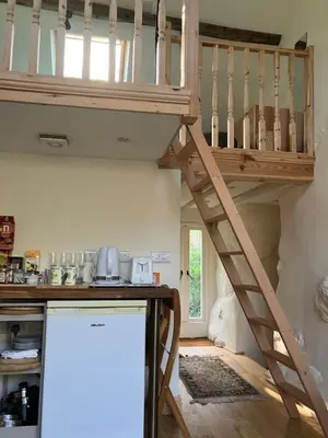 a loft bed in a kitchen with a staircase at Studio in medieval Welsh farmhouse in Aber Cowarch