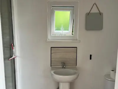 a white bathroom with a sink and a window at Ty Sycamore in Talybont