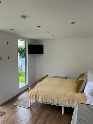 a bedroom with a bed and a television on the wall at Ty Sycamore in Talybont