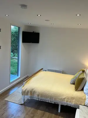 a bedroom with a bed with a television on the wall at Ty Sycamore in Talybont
