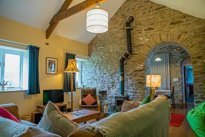 a living room with a stone wall at Cwt Mochyn Aberaeron in Cross Inn