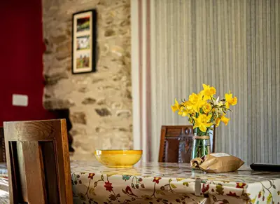 a table with a vase of yellow flowers on it at Cwt Mochyn Aberaeron in Cross Inn