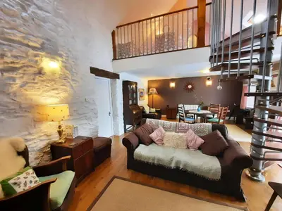 a living room with a couch and a stone wall at Hen Ffermdy Aberaeron in Cross Inn