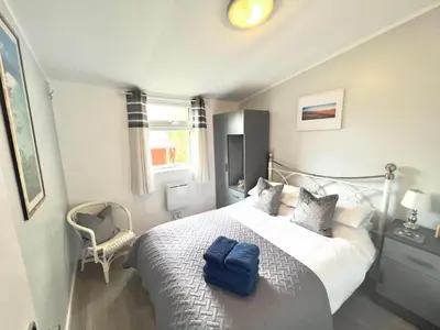 a bedroom with a large bed with blue towels on it at Chalet 7 Erw Porthor in Tywyn