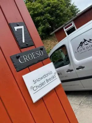 a sign on the side of a house with a car at Chalet 7 Erw Porthor in Tywyn