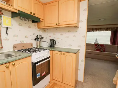 a kitchen with wooden cabinets and a stove top oven at D12 Treetops in Aberystwyth