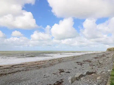 a beach with a cloudy sky and the ocean at D12 Treetops in Aberystwyth