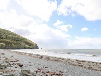 a beach with the ocean and a cloudy sky at D12 Treetops in Aberystwyth