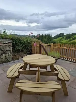 a wooden picnic table and bench on a patio at Rhyd Y Geifr, Cosy Barn Conversion in Maerdy in Corwen