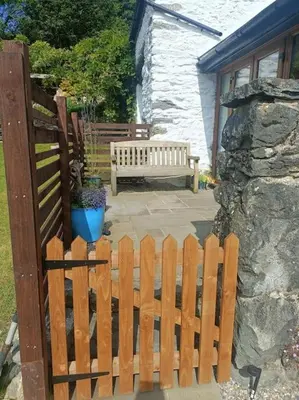 a wooden fence with a bench in a yard at Rhyd Y Geifr, Cosy Barn Conversion in Maerdy in Corwen