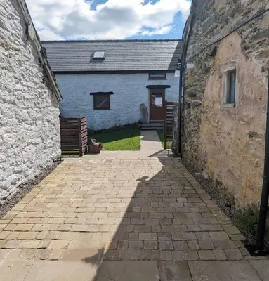 a brick walkway in front of a blue building at Rhyd Y Geifr, Cosy Barn Conversion in Maerdy in Corwen