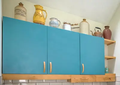 a kitchen cabinet with blue cabinets and utensils at Rhyd Y Geifr, Cosy Barn Conversion in Maerdy in Corwen