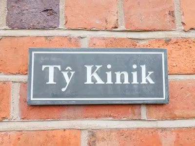 a sign on a brick wall with the words tv kinks at Tŷ Kinik in Llangollen