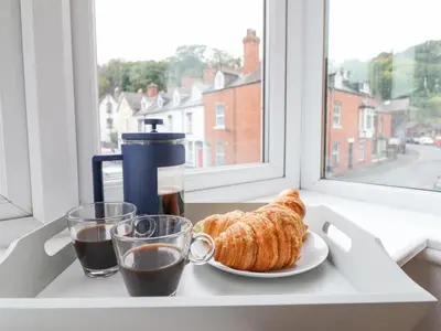 a table with a plate of croissants and coffee and a window at Tŷ Kinik in Llangollen
