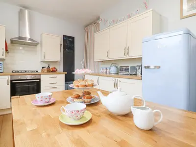 a kitchen with a wooden table with cups and saucers at Tŷ Kinik in Llangollen