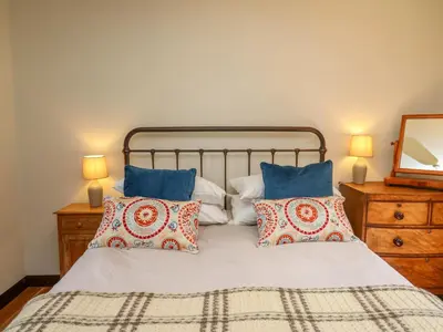 a bedroom with a bed with pillows and a mirror at Oak Apple Cottage in Presteigne