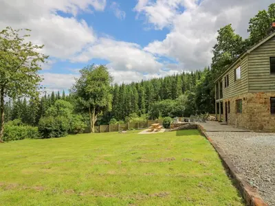 a large yard next to a house with a grass field at Oak Apple Cottage in Presteigne