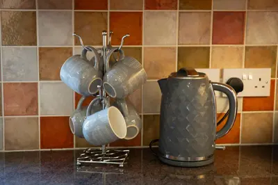a bunch of cups are hanging on a counter at Aberystwyth Dinas Cottage in Llanilar