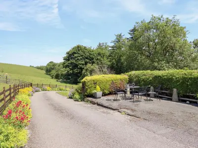 a dirt road with tables and chairs and flowers at Bryn Bras in Corwen