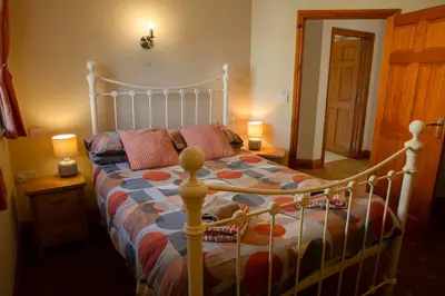 a bedroom with a large bed with a wooden frame at Aberystwyth Enlli Cottage in Llanilar