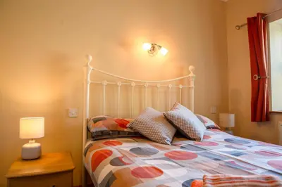 a bedroom with a bed and a lamp on a table at Aberystwyth Enlli Cottage in Llanilar
