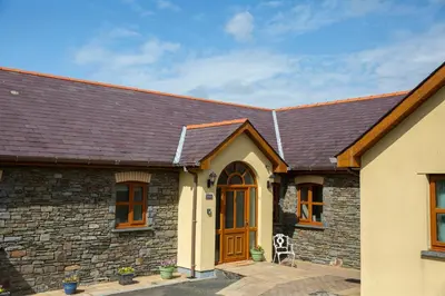 a stone house with a wooden door and a roof at Aberystwyth Enlli Cottage in Llanilar