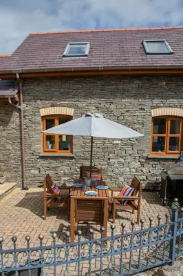 a patio with a table and chairs and an umbrella at Aberystwyth Cottage Ilar in Llanilar