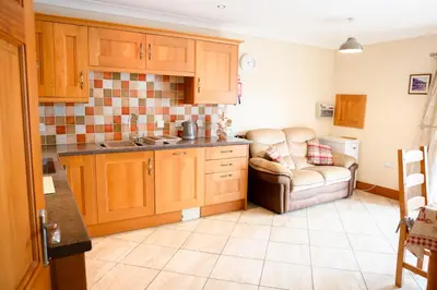 a kitchen with a couch and a chair in it at Aberystwyth Cottage Ilar in Llanilar