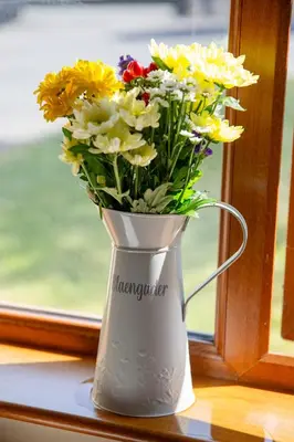 a white vase filled with flowers on a window sill at Aberystwyth Cottage Ilar in Llanilar