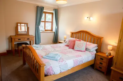 a bedroom with a bed with pink and blue pillows at Aberystwyth Cottage Ilar in Llanilar