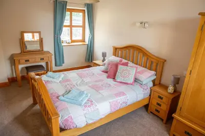 a bedroom with a bed with pink and blue pillows at Aberystwyth Cottage Ilar in Llanilar