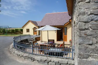 a house with an outdoor patio with an umbrella at Aberystwyth Cottage Ilar in Llanilar