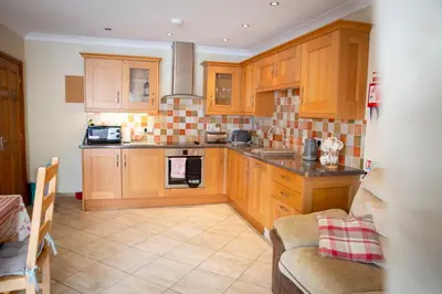 a kitchen with wooden cabinets and a stove at Aberystwyth Cottage Ilar in Llanilar