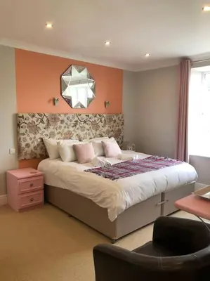 a bedroom with a large bed and a chair at Cartref Guesthouse - Room 1 Ensuite in Aberdyfi
