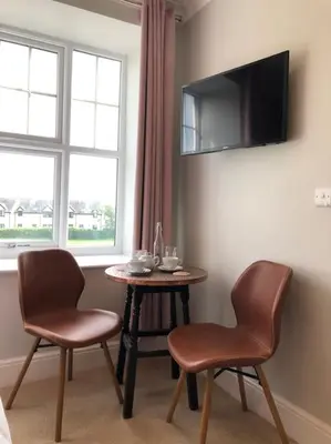 a room with two chairs and a table and a tv at Cartref Guesthouse - Room 1 Ensuite in Aberdyfi