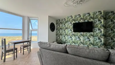 a living room with a couch and a tv on a wall at Barmouth Beach Front Apartments in Barmouth