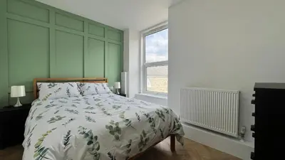 a bedroom with a bed and a large window at Barmouth Beach Front Apartments in Barmouth